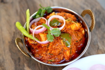 Butter chicken mutton curry or Indian style cottage cheese curry in a brass bowl with Salads.