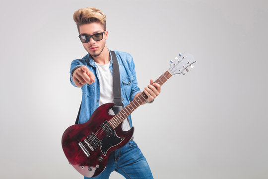 man wearing sunglasses and playing guitar in studio