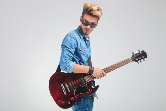 portrait of man looking down in studio while holding a guitar