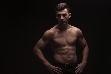 Fototapeta na wymiar topless muscular guy posing in dark studio background