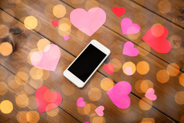 close up of smartphone and hearts on wood