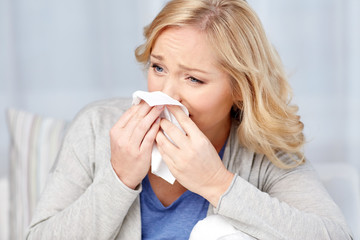 ill woman blowing nose to paper napkin