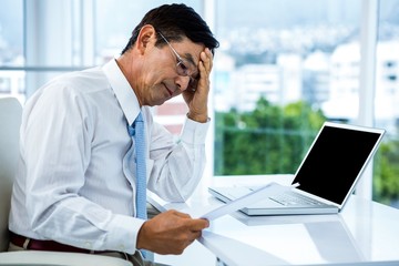 Naklejka premium Worried businessman working at his desk