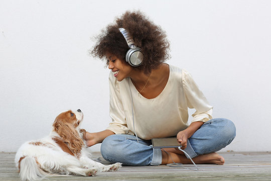 young african american black woman listening music on tablet with headphones.Dog laying down.