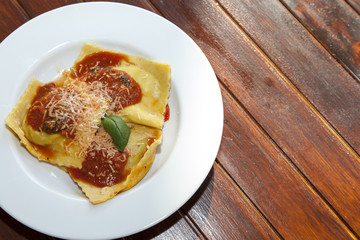 Delicius italian pasta, Ravioli on white plate, for stuffing is used organic vegetables, decorated with tomato sauce, fresh Mediterranean basil and parmesan, Parma cheese, selective focus, close up 