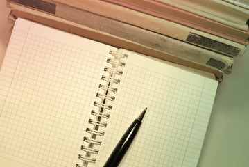 Pen, notebook with blank pages and old books in retro vintage tone effect