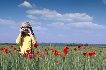 little girl with camera on spring meadow