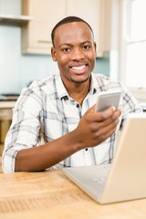 Handsome man holding smartphone in the kitchen