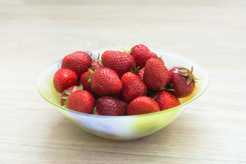Plate with strawberries on a light blurred background.