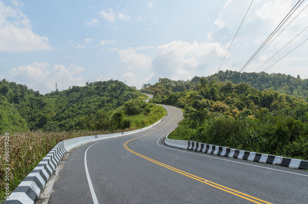 Wall mural curve of empty road and green field in country at nan thailand