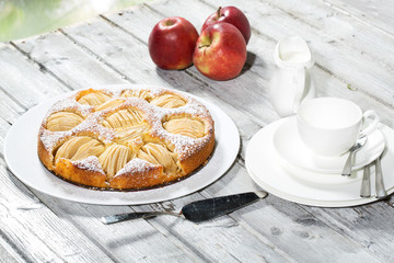 Apfelkuchen, Kaffeetasse und Teller, Äpfel auf Holz
