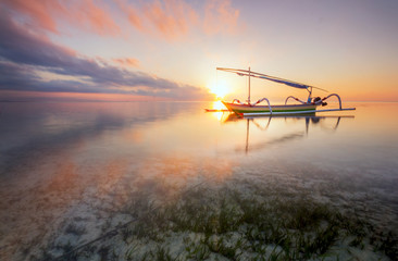 Twilight Sunrise at Sanur Beach Bali with traditional balinese jukung