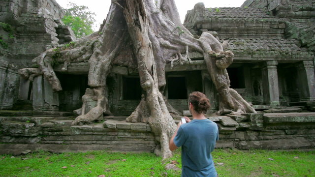 visitor taking picture bizarre nature of preah khan temple, angkor