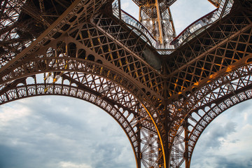 Close-up elements part of Eiffel tower in Paris against dramatic twilight sky at evening summer time.