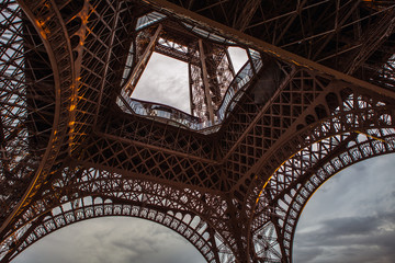 Close-up elements part of Eiffel tower in Paris against dramatic twilight sky at evening summer time.