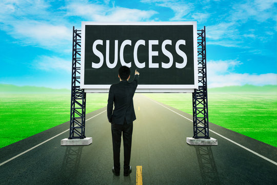 businessman standing on road and pointing with large sign of suc