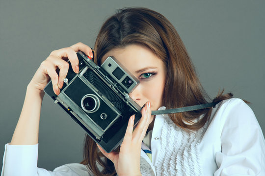 Pretty young girl with retro vintage camera.  Grey background