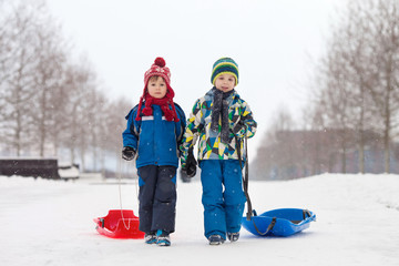 Two kids, boy brothers, sliding with bob in the snow, wintertime