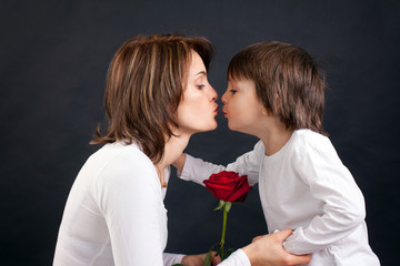 Young kid giving gorgeous red rose to his mom