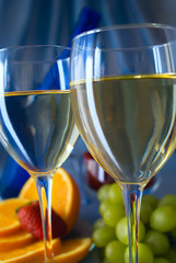 Clouseup of glasses of white wine with oranges and grapes