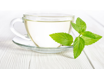 Glass cup of tea with mint on the white wooden table