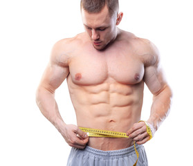 Image of muscular man measure his waist with measuring tape in centimeters. Shot isolated on white background