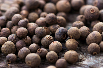 Allspice pepper on the rustic wooden background