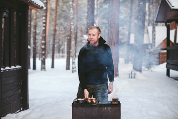 bearded man a fish fry on the grill in the winter forest