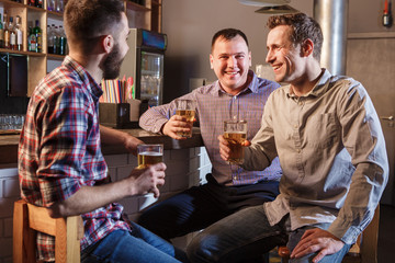 Happy friends drinking beer at counter in pub