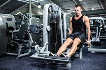 Fototapeta na wymiar Muscular man using exercise machine for legs