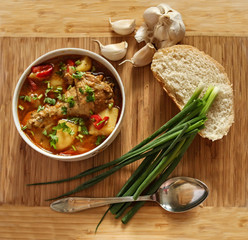 Food - Chicken soup with potatoes and tomatoes, garlic, onion, bread - wood background