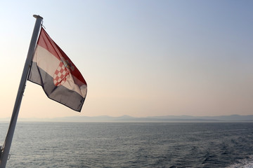 Flag of Croatia in the wind, above the sea, at sunset. With copy space.