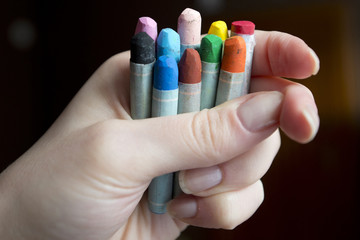 Kilka kolorowych pasteli olejnych trzymanych przez kobietę w dłoni.  - obrazy, fototapety, plakaty