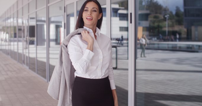 Independent beautiful business woman standing outside of office building with folded arms and jacket over shoulder