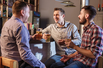 Happy friends drinking beer at counter in pub