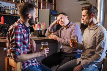 The  friends drinking beer at counter in pub