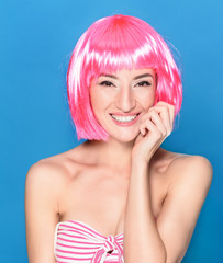 Portrait of beautiful smiling young woman with pink hair on a blue background