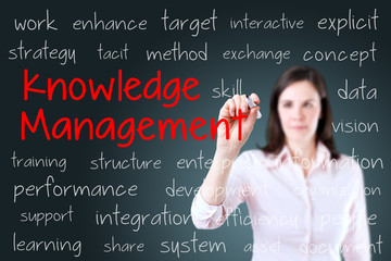 Businesswoman writing knowledge management concept. Blue background.