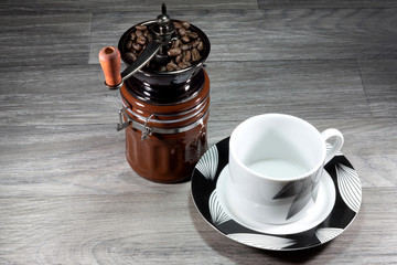 Eine altmodische Kaffeemühle und eine leere Tasse