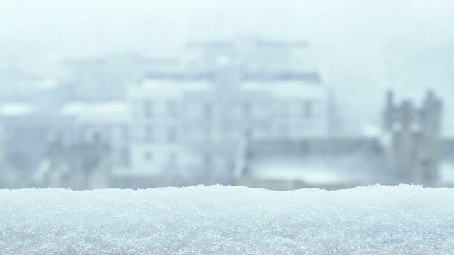 Snow. Falling from window snowflakes with selective focus with city view. Cold winter concept.
