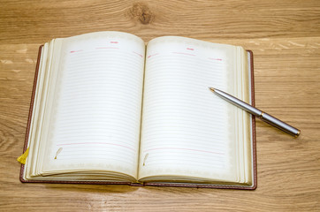 top view of old open book with fountain pen on wooden table