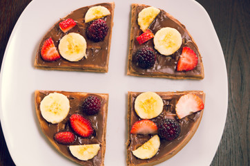 Pancake cut in four parts decorated with fruits, glass of orange juice and a boiled egg