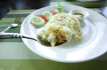 Rice in spoon with fried rice recipe as background.