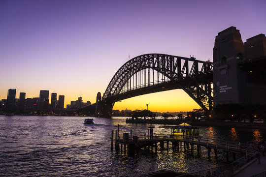 A silhouette of Sydney harbour bridge at sunset.