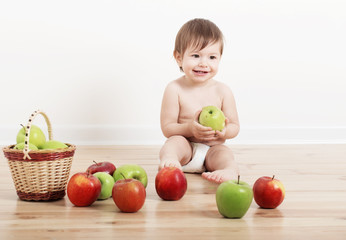 Fototapeta na wymiar Portrait of a cute little child with apples indoor
