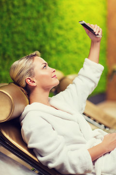 beautiful young woman with smartphone at spa