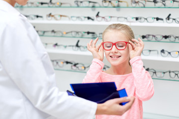 optician and girl choosing glasses at optics store