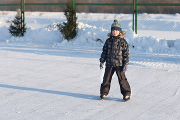 Fototapeta na wymiar Happy child skating in winter at the rink. Cheerful children walk and play outside on the ice.