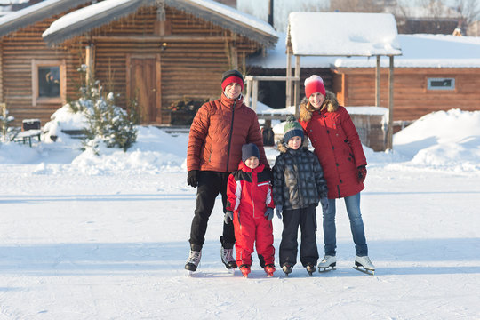 Happy Young Family Skate At The Rink In The Winter. Beautiful Family Walking And Playing On The Ice In Winter.