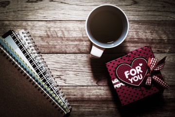 Gift box, notebooks and coffee on wooden plank